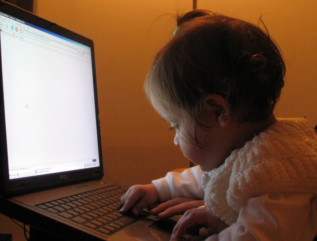 Dítě sledující klávesnici notebooku